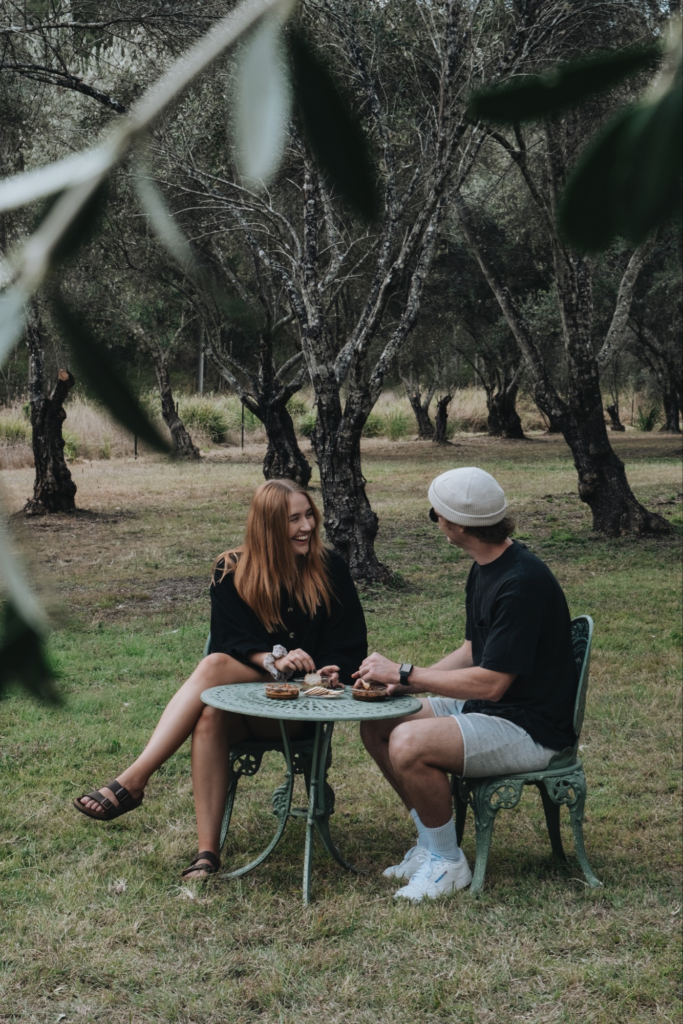 Couple sitting in grove eating olives